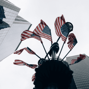 American flags between skyscrapers, low-angle view.