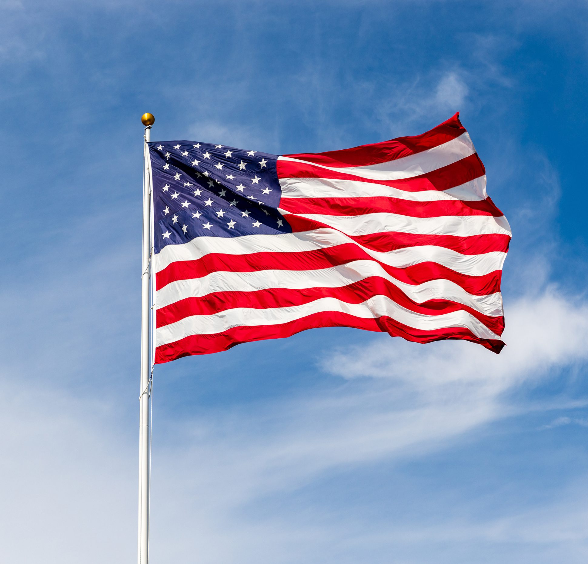 American flag waving against blue sky.